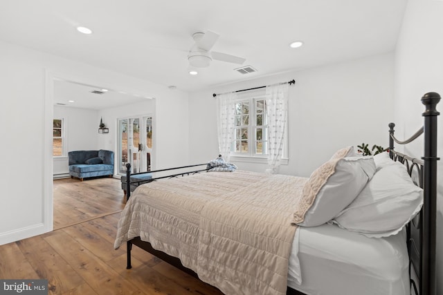 bedroom with hardwood / wood-style flooring, ceiling fan, and baseboard heating