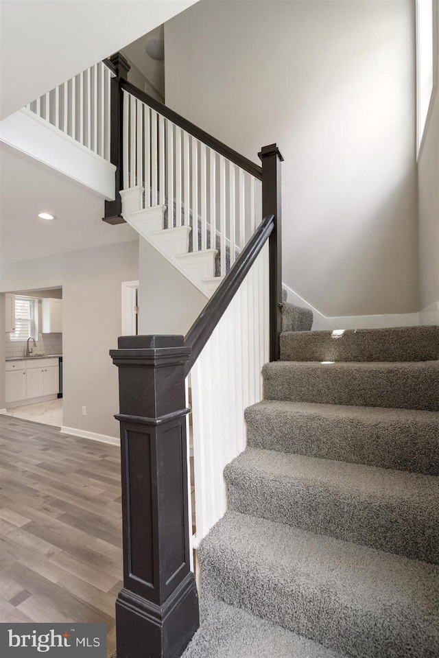 stairway with hardwood / wood-style floors, a towering ceiling, and sink