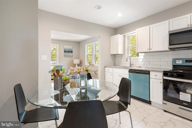 kitchen with white cabinetry, sink, light stone counters, decorative backsplash, and appliances with stainless steel finishes