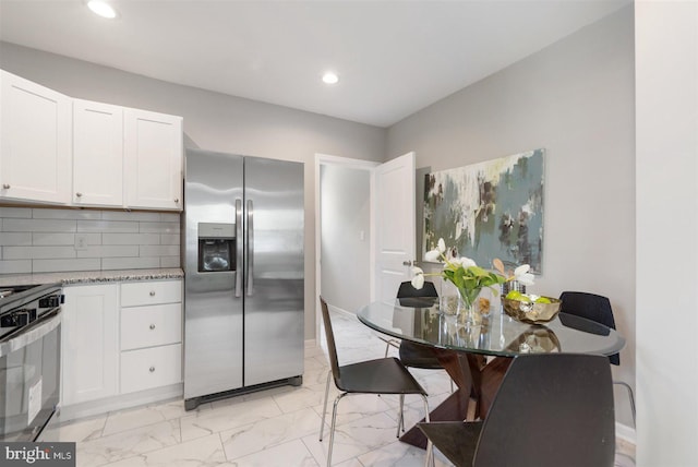 kitchen with white cabinets, appliances with stainless steel finishes, decorative backsplash, and light stone counters