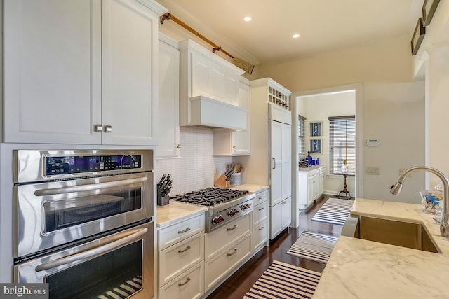 kitchen featuring white cabinetry, light stone countertops, appliances with stainless steel finishes, sink, and tasteful backsplash