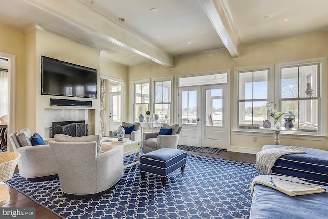 living room featuring a tiled fireplace, hardwood / wood-style flooring, ornamental molding, beamed ceiling, and french doors