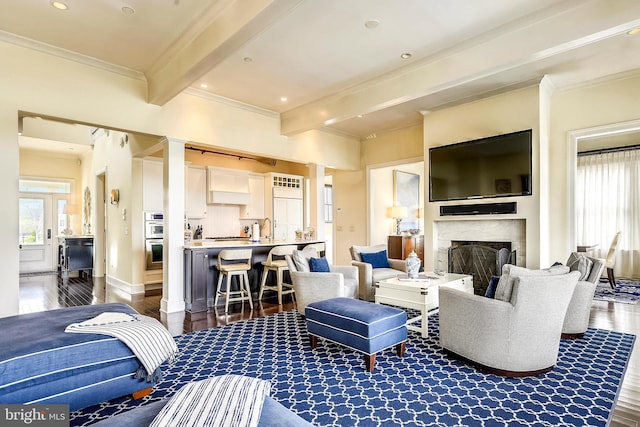 living room featuring beamed ceiling, wood-type flooring, a high end fireplace, and ornamental molding