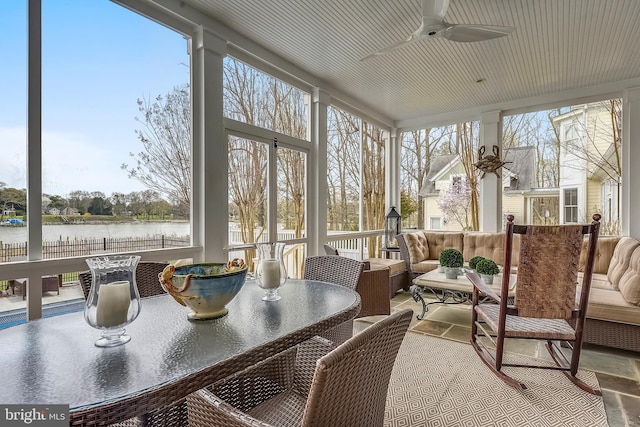 sunroom / solarium featuring ceiling fan and a water view