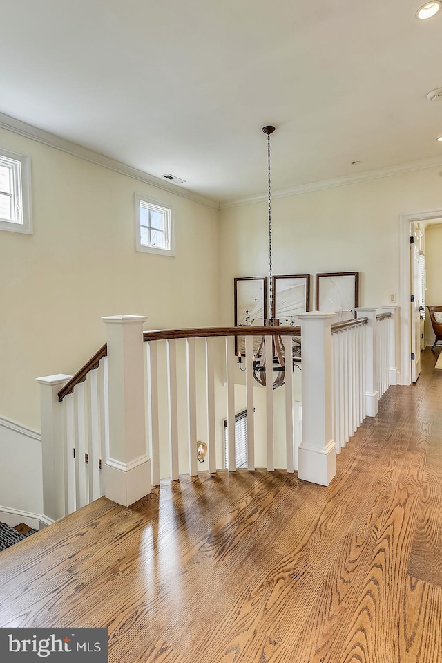 corridor featuring ornamental molding, light hardwood / wood-style flooring, and a chandelier