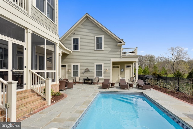 back of house with a patio, a sunroom, a balcony, and a fenced in pool