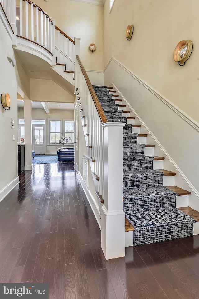 stairs with a towering ceiling and dark hardwood / wood-style floors