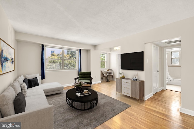 living room featuring light wood-type flooring and a textured ceiling