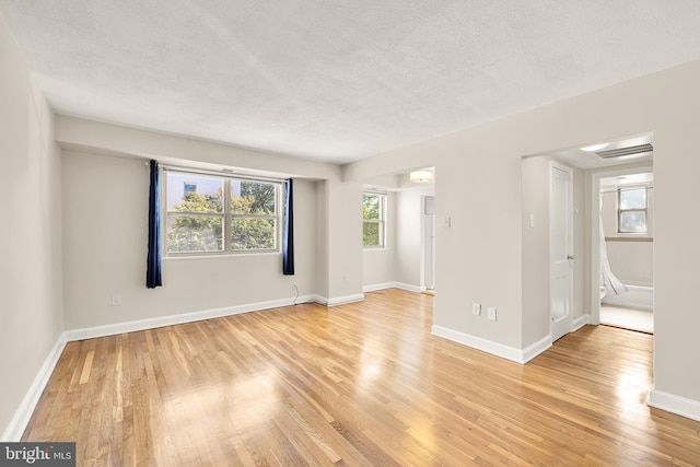 spare room with a textured ceiling and light hardwood / wood-style floors