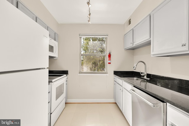 kitchen featuring rail lighting, dark stone countertops, white appliances, sink, and white cabinetry