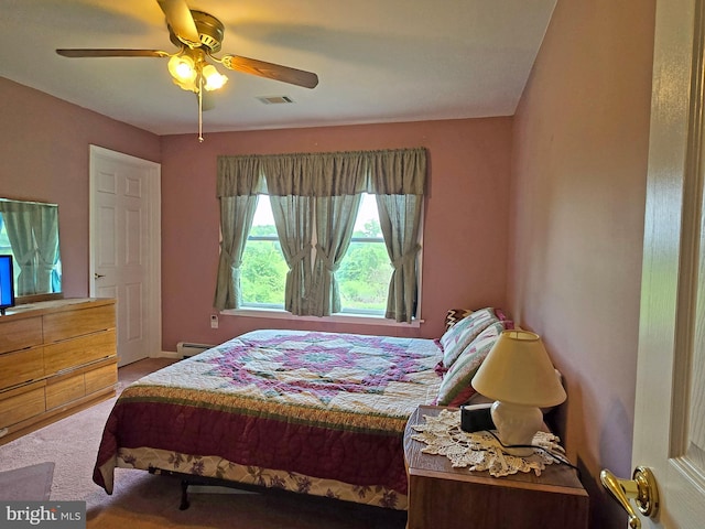 carpeted bedroom featuring ceiling fan and a baseboard heating unit