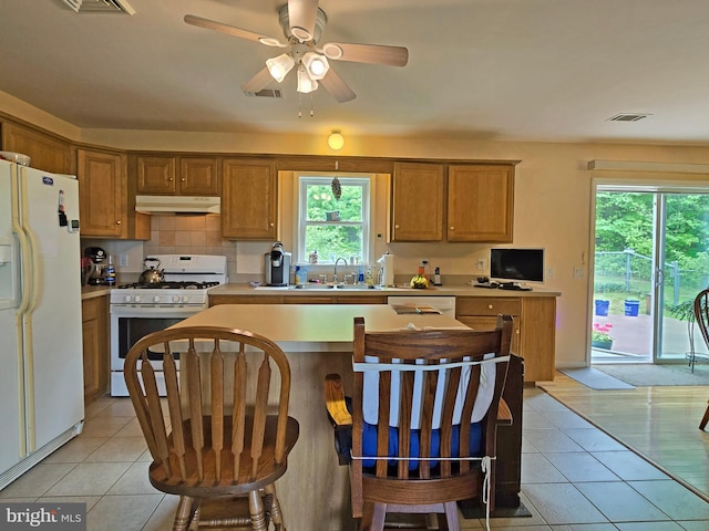 kitchen with white appliances, light tile patterned floors, ceiling fan, decorative backsplash, and sink