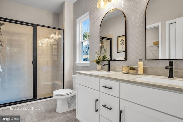 bathroom featuring vanity, a shower with shower door, tile patterned floors, toilet, and decorative backsplash