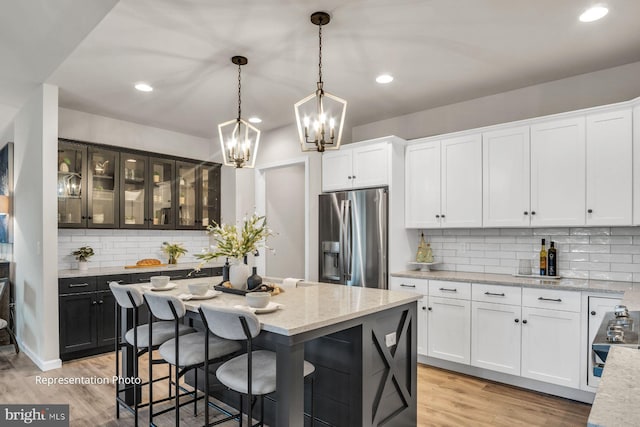 kitchen featuring pendant lighting, light wood-type flooring, stainless steel fridge with ice dispenser, and tasteful backsplash