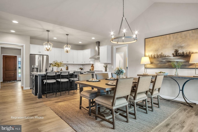 dining area featuring vaulted ceiling, a notable chandelier, and light hardwood / wood-style floors