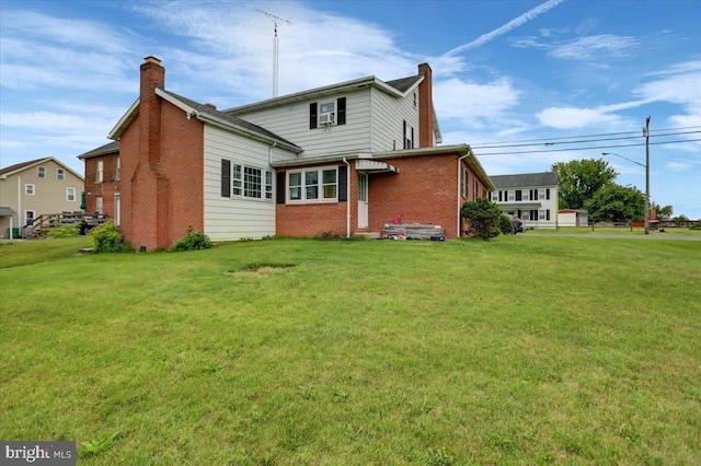 back of property featuring a chimney, a yard, and brick siding