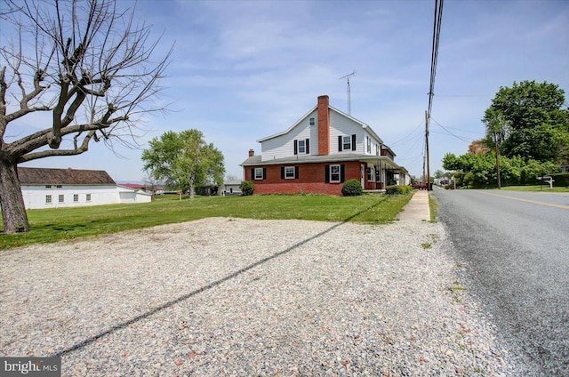 exterior space with a yard, brick siding, driveway, and a chimney