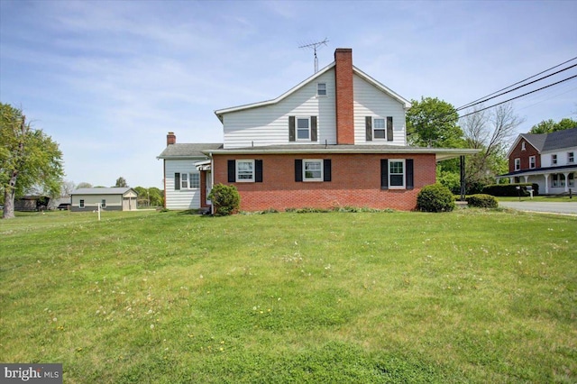 back of house with a chimney, a yard, and brick siding