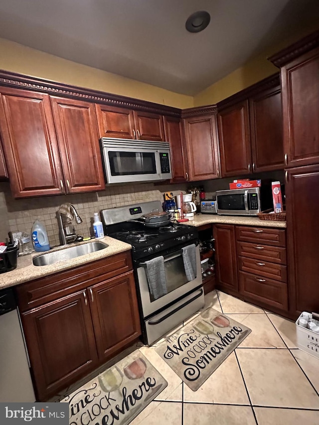 kitchen featuring appliances with stainless steel finishes, sink, tasteful backsplash, and light tile floors