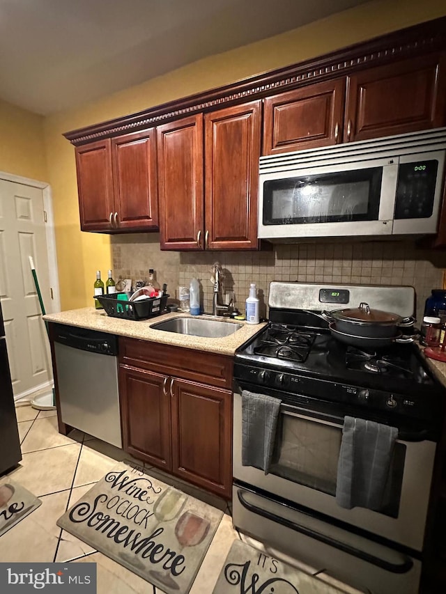 kitchen with stainless steel appliances, sink, tasteful backsplash, and light tile floors