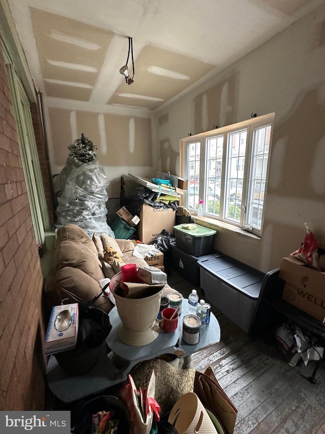 living room with brick wall and wood-type flooring