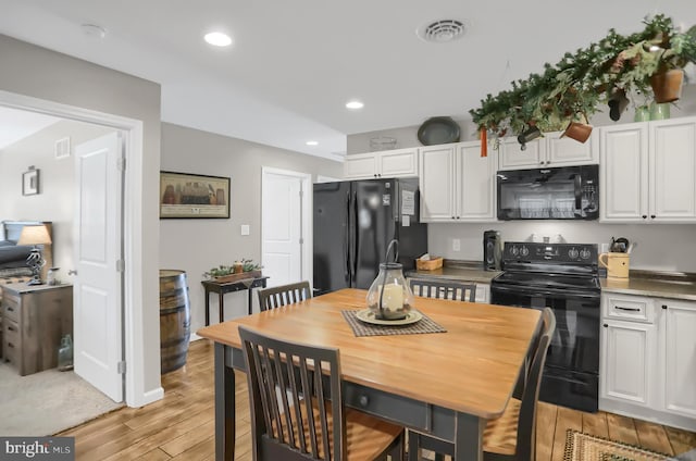 kitchen with white cabinets, black appliances, and light hardwood / wood-style flooring