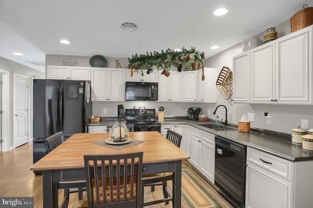 kitchen with sink, light hardwood / wood-style floors, white cabinets, and black appliances