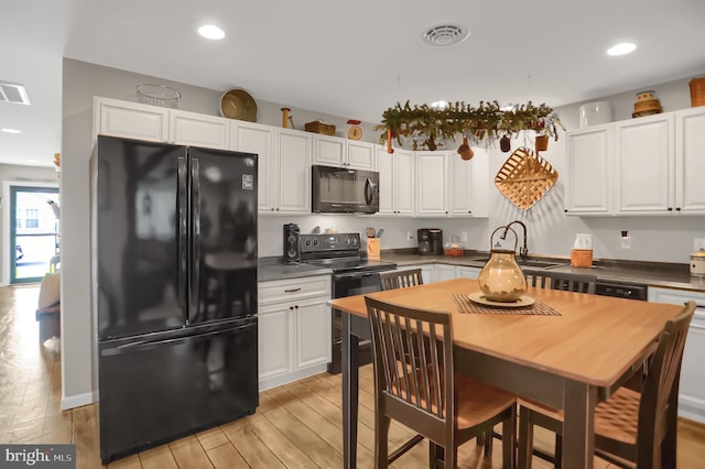 kitchen with white cabinetry, black appliances, sink, and light wood-type flooring