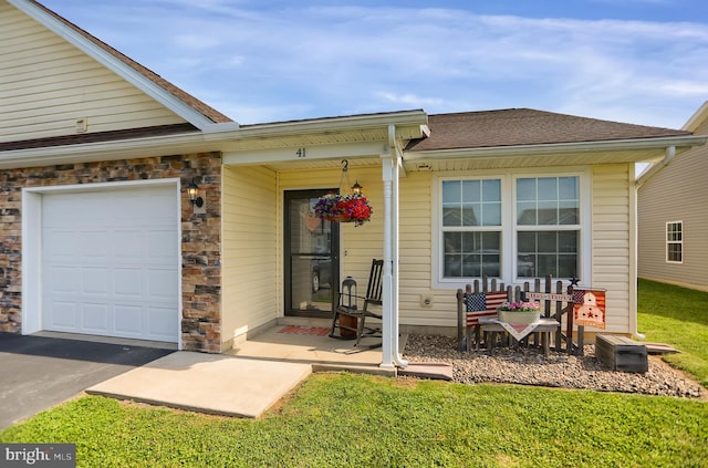 doorway to property with a garage and a lawn