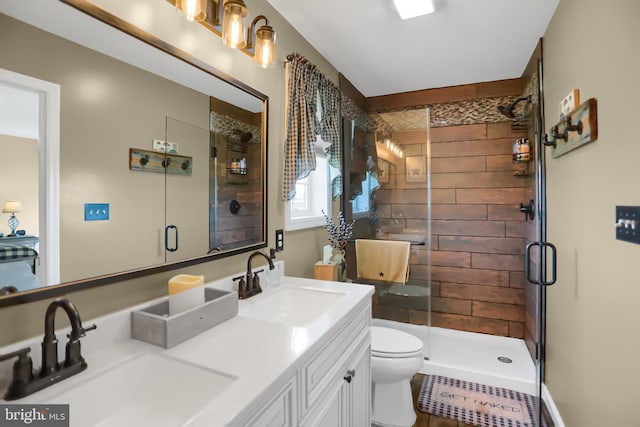 bathroom featuring a shower with door, dual bowl vanity, and toilet