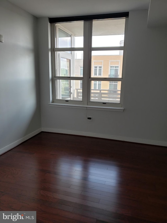 unfurnished room featuring a wealth of natural light and dark hardwood / wood-style floors