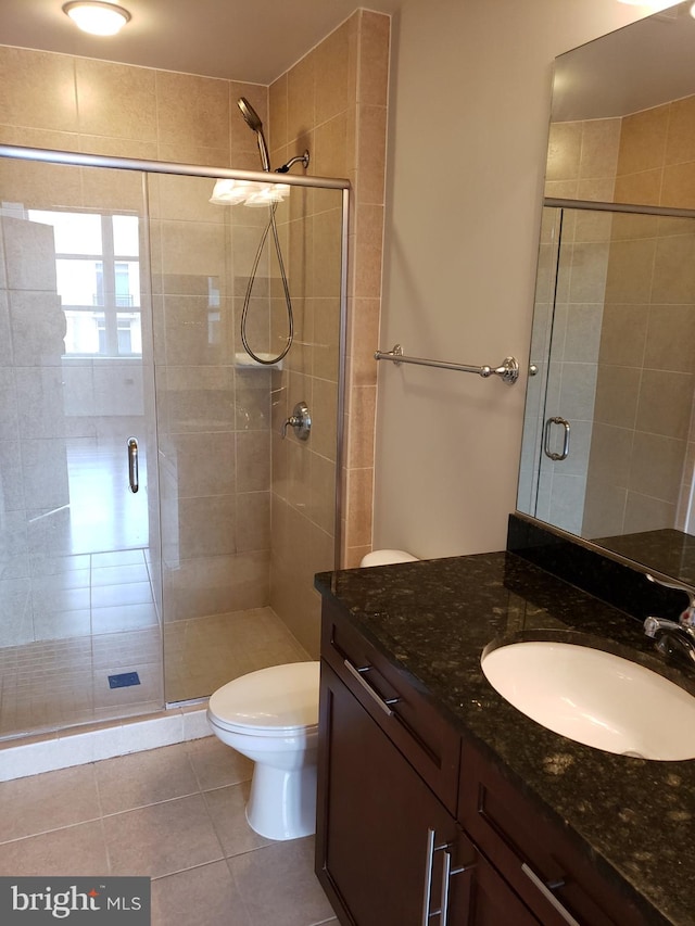 bathroom with a shower with shower door, tile flooring, vanity, and toilet