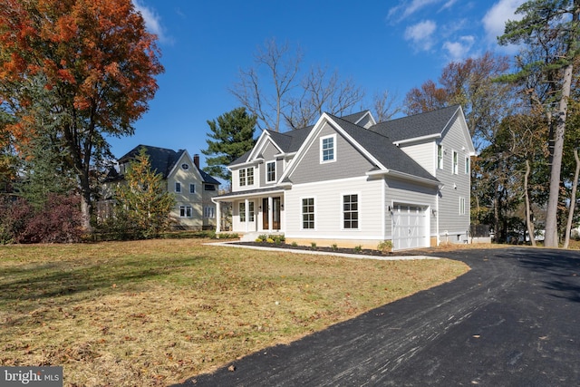 view of front of property featuring a porch, a garage, and a front yard