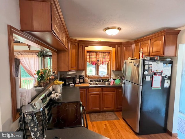 kitchen featuring a textured ceiling, light wood-type flooring, sink, and appliances with stainless steel finishes