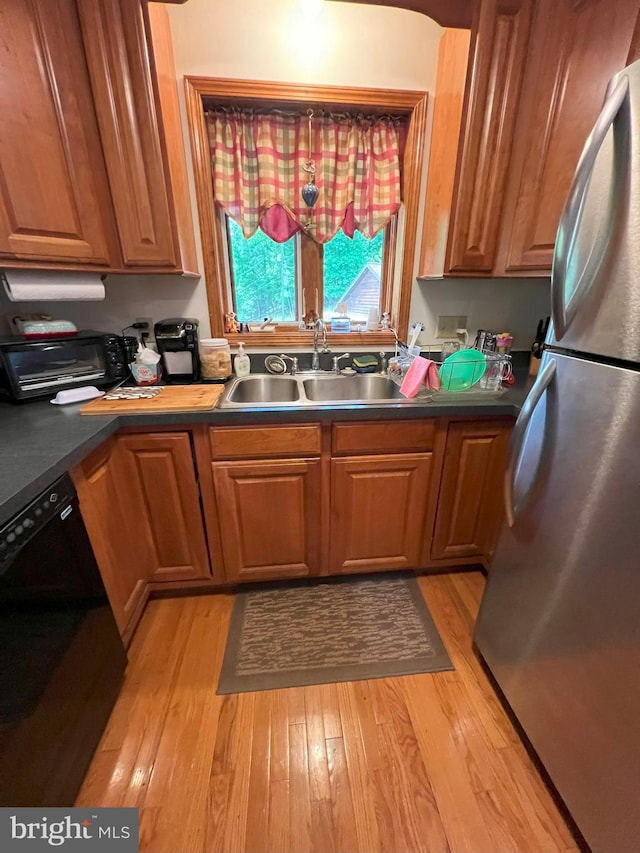 kitchen with stainless steel fridge, sink, light hardwood / wood-style floors, and black dishwasher