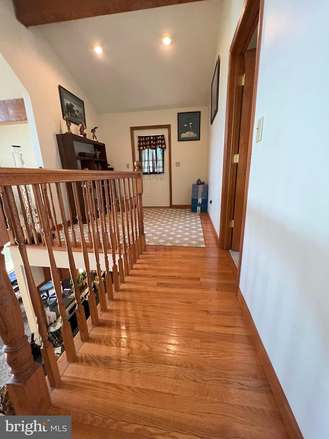 corridor with vaulted ceiling with beams and light hardwood / wood-style floors