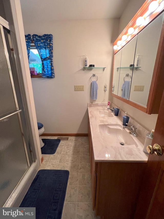 bathroom with tile patterned floors, vanity, toilet, and a shower with shower door