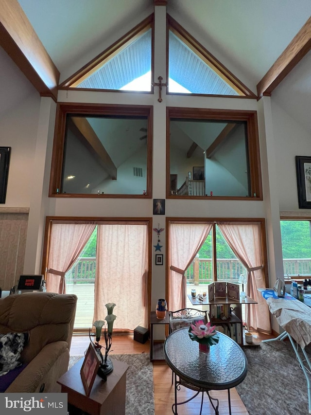 living room with vaulted ceiling with beams, a healthy amount of sunlight, and wood-type flooring