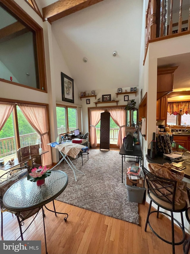 living room featuring beamed ceiling, hardwood / wood-style floors, high vaulted ceiling, and sink