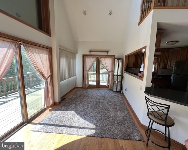 living room with french doors, light hardwood / wood-style floors, and high vaulted ceiling