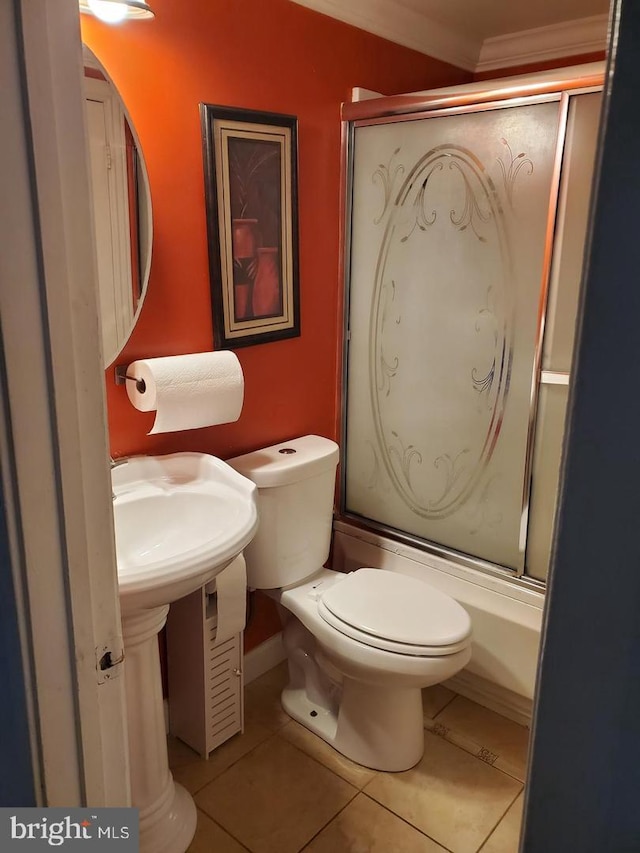 bathroom with tile patterned floors, combined bath / shower with glass door, ornamental molding, and toilet