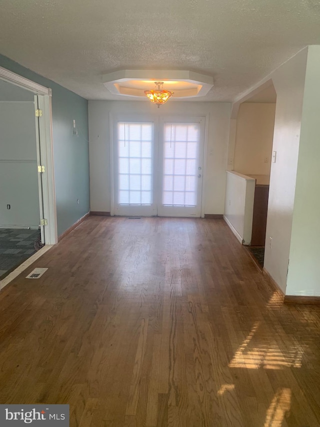 spare room featuring a textured ceiling, a tray ceiling, and dark hardwood / wood-style floors