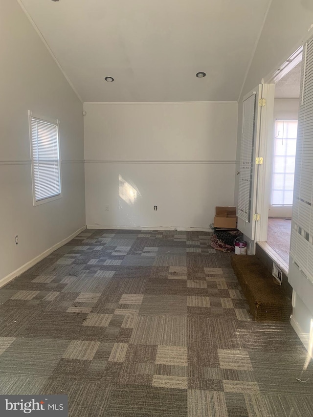 carpeted empty room with lofted ceiling