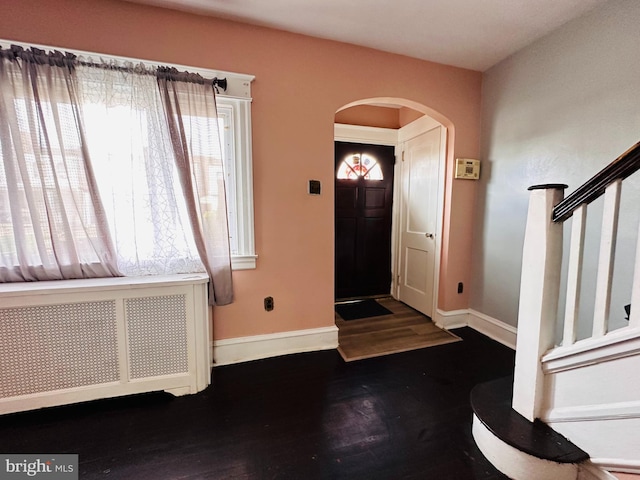 foyer entrance with dark wood-type flooring and radiator heating unit