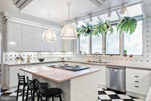 kitchen with stainless steel appliances, a kitchen island, sink, and light tile floors