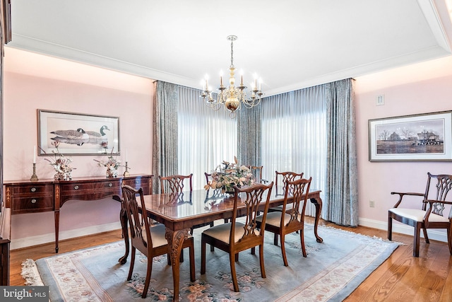 dining room with a notable chandelier, light wood-type flooring, and crown molding