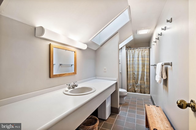 bathroom with tile flooring, vanity with extensive cabinet space, toilet, and vaulted ceiling with skylight