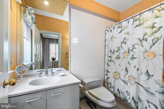 bathroom with tile walls, tile floors, toilet, and vanity with extensive cabinet space