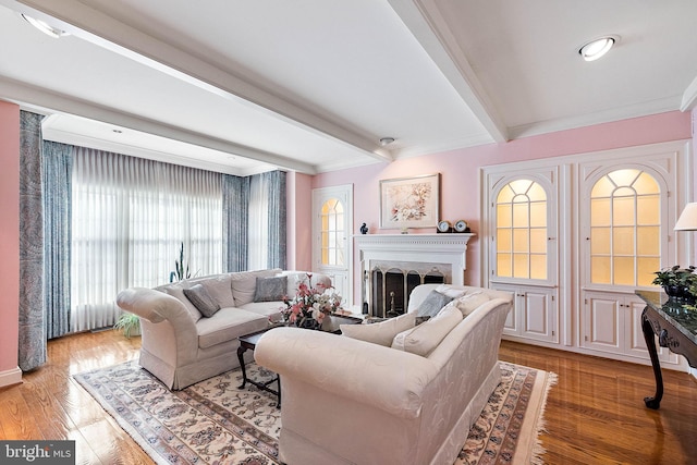 living room featuring beamed ceiling, ornamental molding, and wood-type flooring