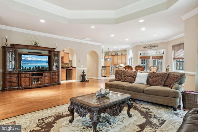 living room featuring wood-type flooring, ornamental molding, and a raised ceiling